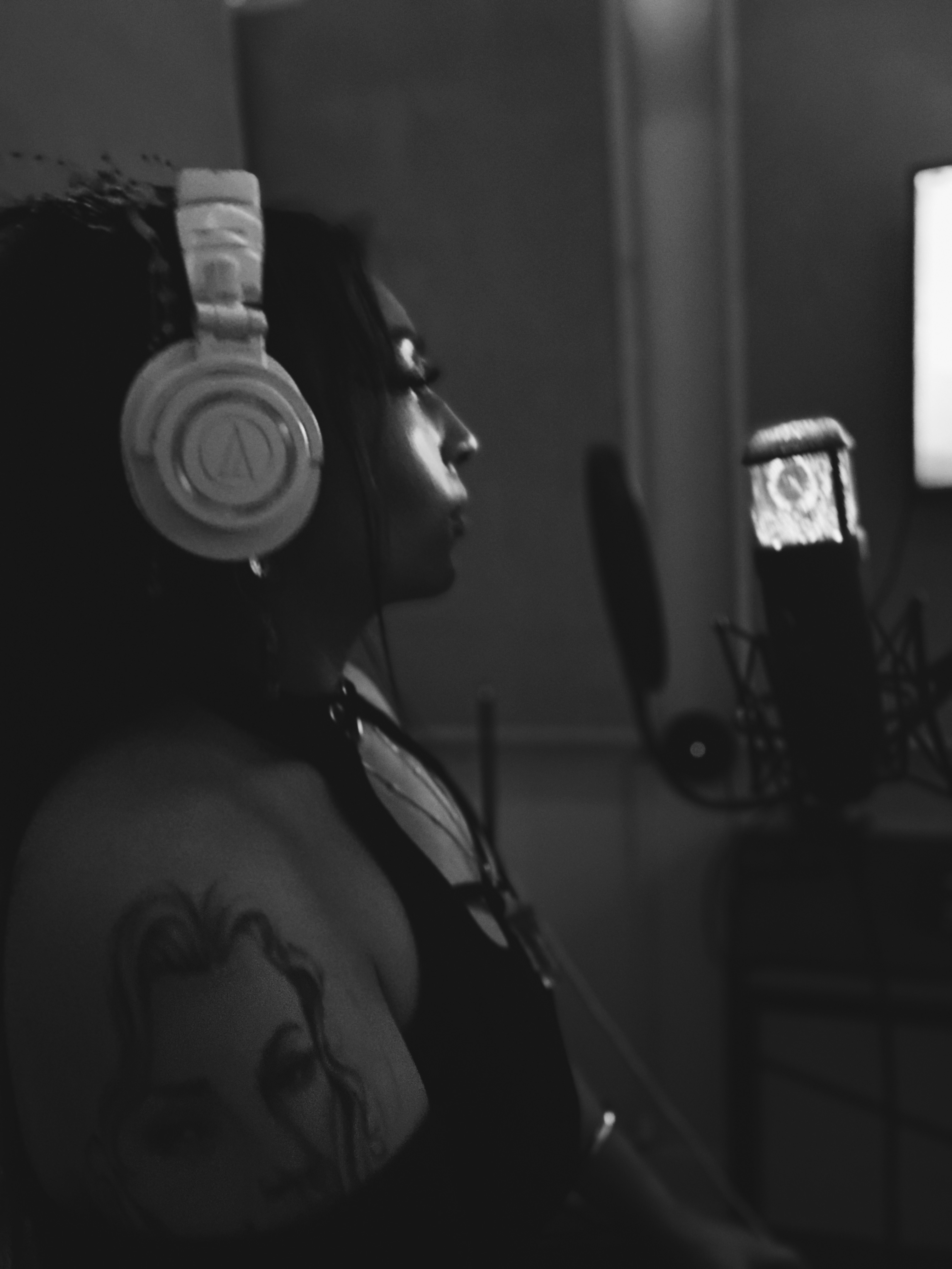 Artist wearing headphones at a studio microphone.