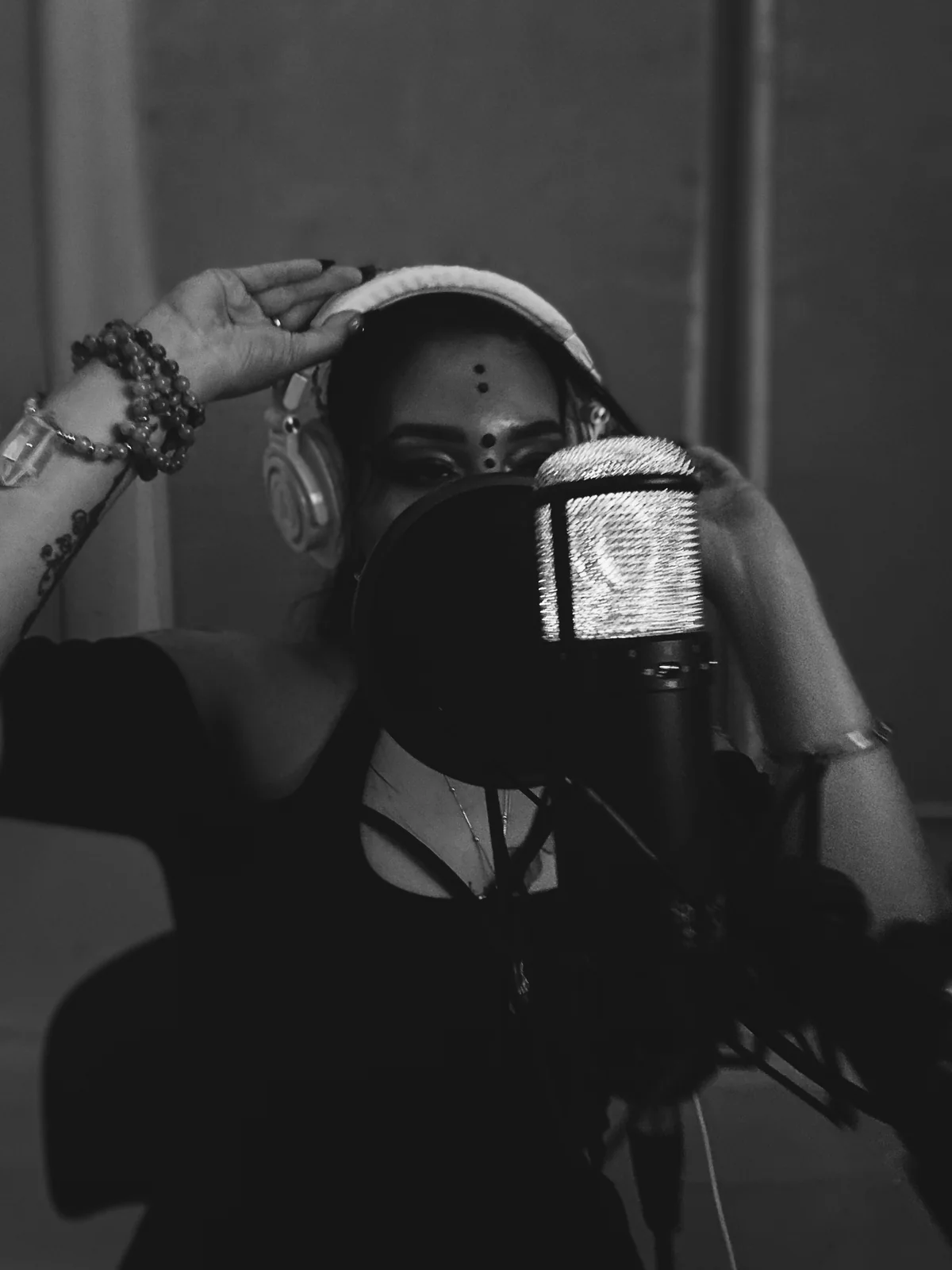 An artist tracking vocals at a studio microphone.